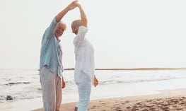 older couple on beach prioritizing their health and wellness   